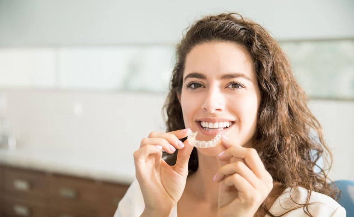 retrato-hermosa-paciente-sosteniendo-retenedores-ortodoncia-clinica-dental